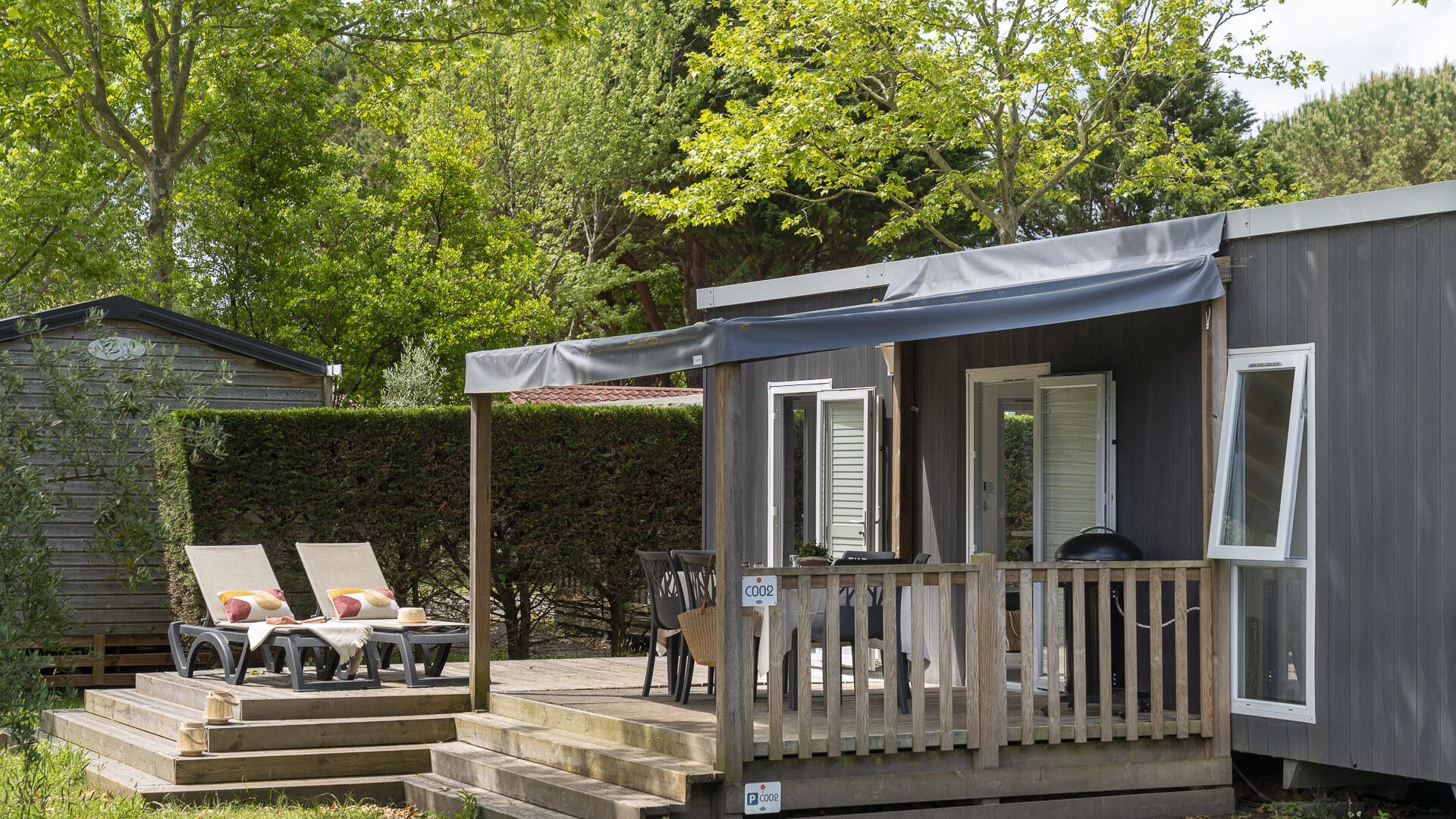 Mobil-home avec terrasse en bois et transats.