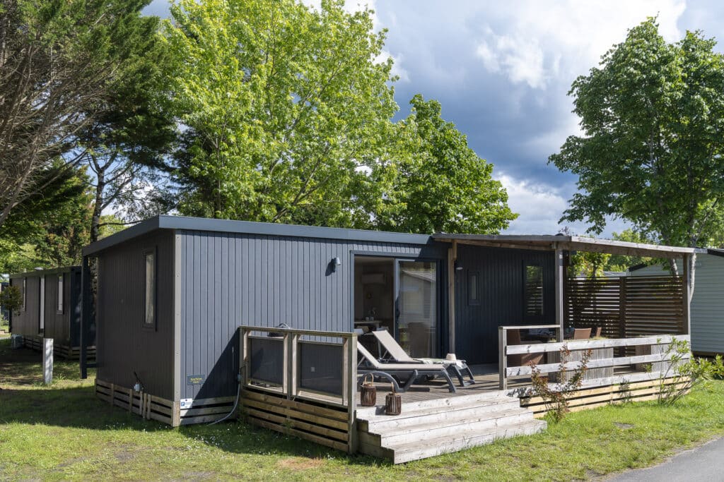 Mobil-home moderne avec terrasse en bois, journée ensoleillée.