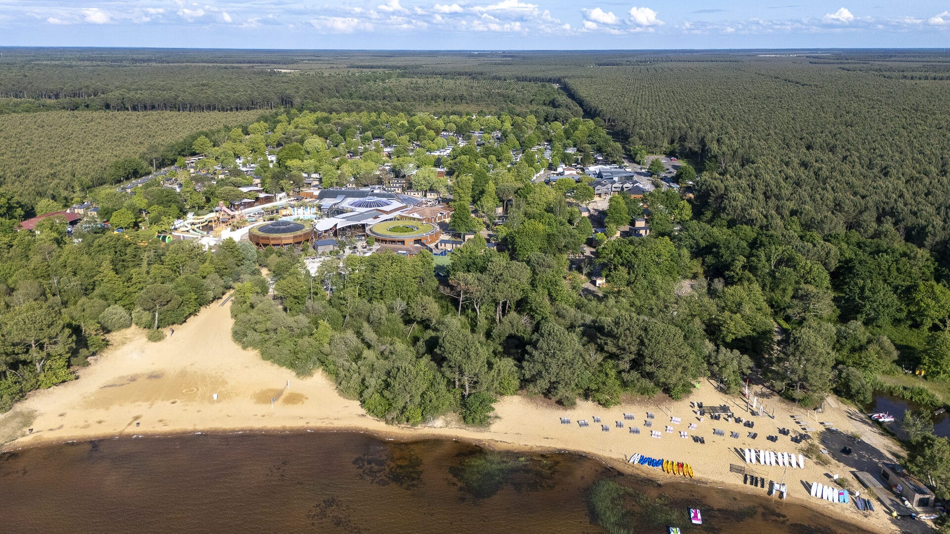 Vue aérienne d'un camping avec plage et forêt.